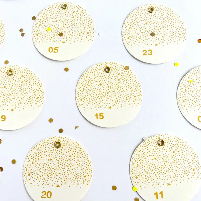 24 runde Adventskalender-Zahlenanhänger aus Naturpapier mit goldfarbenen Metallösen im funkelnden Stempel-Design, ideal zum Basteln von DIY Adventskalendern, um Freunde, Familie oder Partner zu überraschen